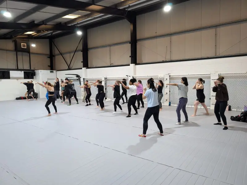 A large class of women practising striking drills