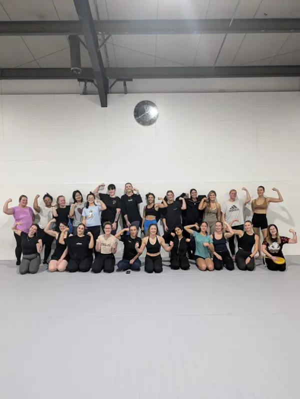 A large group of women flexing their arms and smiling after a session
