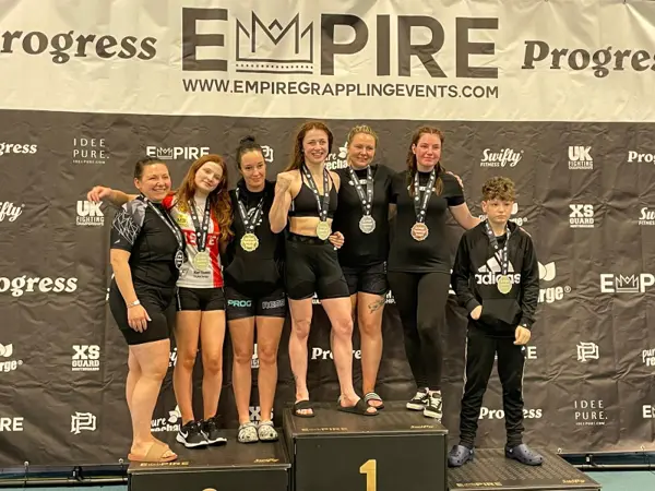 Women standing on the podium with their medals at a grappling competition