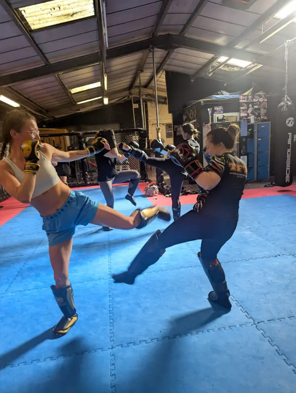 A woman throwing a kick at her partner while drilling on the mats