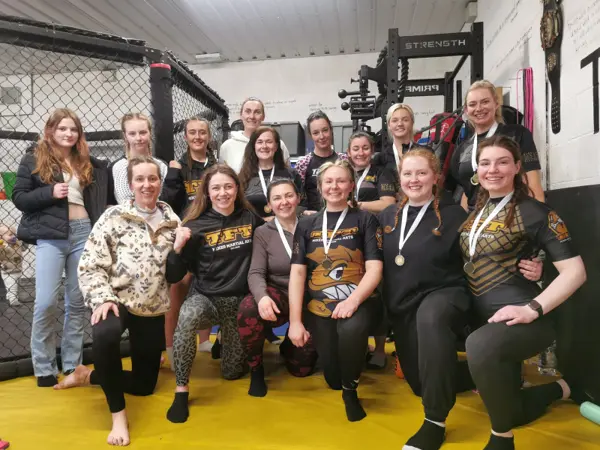 A large group of women with medals posing together in front of the cage