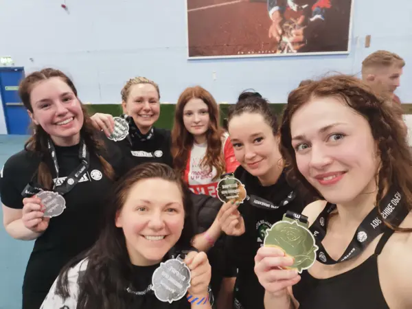 A group selfie of smiling women holding up their medals