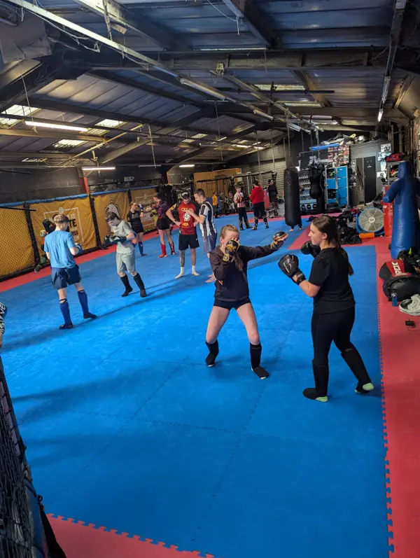 Pairs of women drilling striking on pads across a large gym