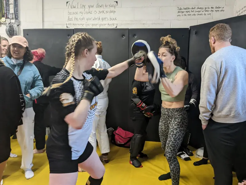 A woman throwing a jab at pads during a striking seminar