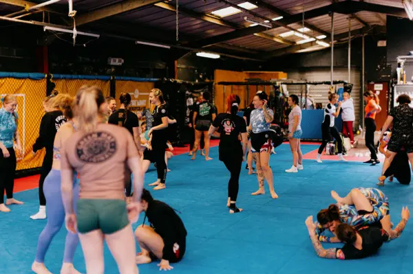 A busy mat of women drilling wrestling techniques in pairs at WOC 2