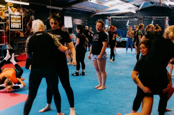 Pairs of women working on clinch positions across the gym