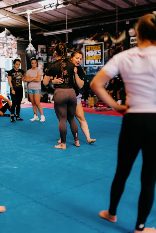 Women drilling wrestling positions in a large training hall