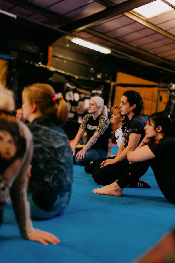 Women sitting on the mats watching a technique demonstration