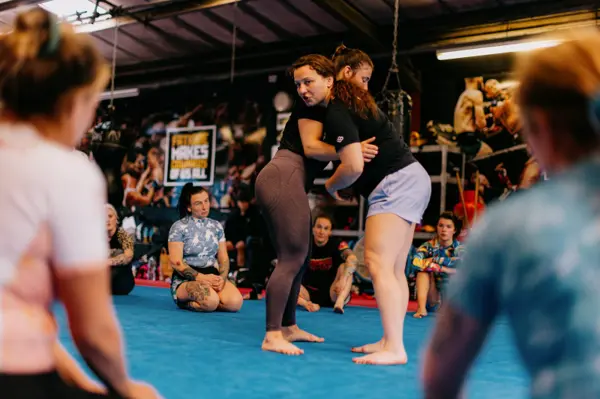 A technique being demonstrated as attendees watch from the mats