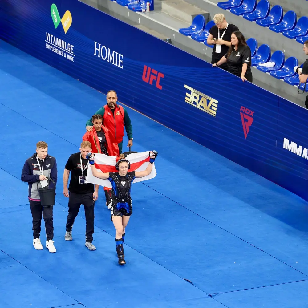 Katrina Fisher raising the England flag as she walks out with Team England coaches